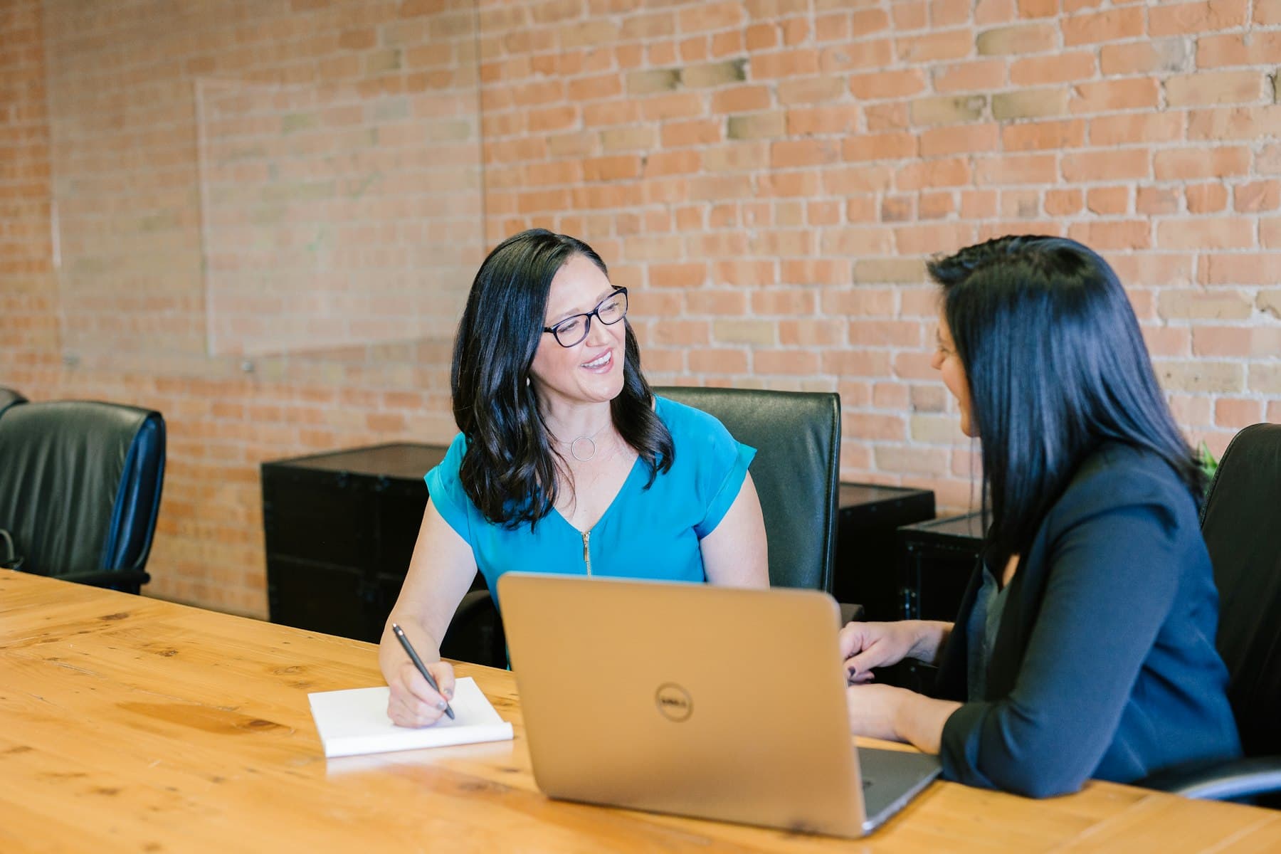 Two professionals discussing a business plan across a desk with a laptop